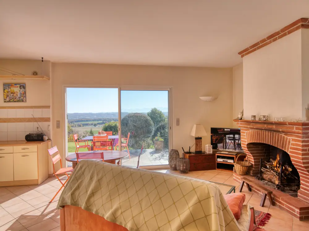 Salon confortable avec cheminée traditionnelle et baie vitrée lumineuse dans le Gers